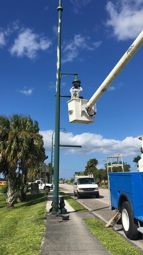 Outdoor Pole Light Troubleshooting: 7 Fast, Proven Fixes 1 An Electrical Technician In An Elevated Bucket Truck Works On A Tall Green Outdoor Pole Light Fixture, Performing Comprehensive Outdoor Pole Light Troubleshooting On A Sunny Day.